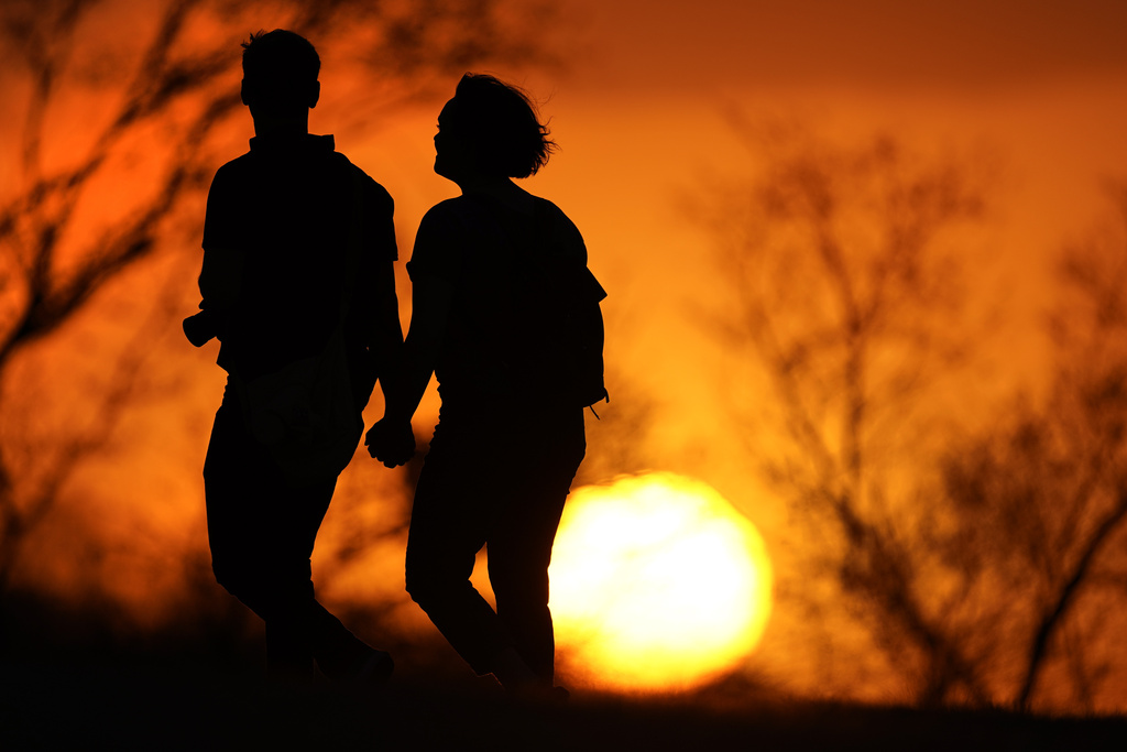 FILE - A couple walks through a park at sunset, March 10, 2021, in Kansas City, Mo. U.S. life expectancy rose in 2022 — by more than a year — after plunging two straight years at the beginning of the COVID-19 pandemic, according to a new government report released Wednesday, Nov. 29, 2023. The rise was mainly due to the waning of the pandemic in 2022, researchers said at the Centers for Disease Control and Prevention. (AP Photo/Charlie Riedel, File)