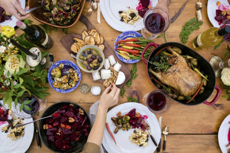 The image features various holiday foods spread around a table creating a scene of abundant and delicious classic seasonal foods that are enjoyed by people.